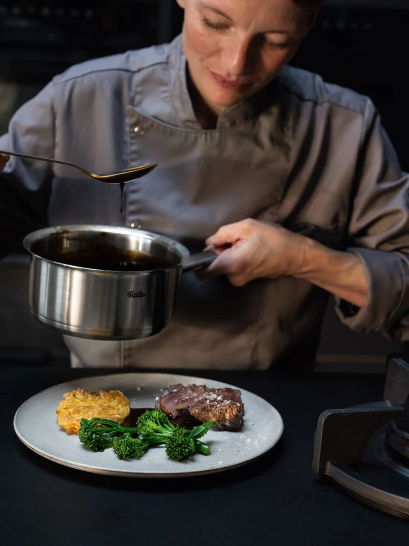 Chef drizzling sauce over plated dish